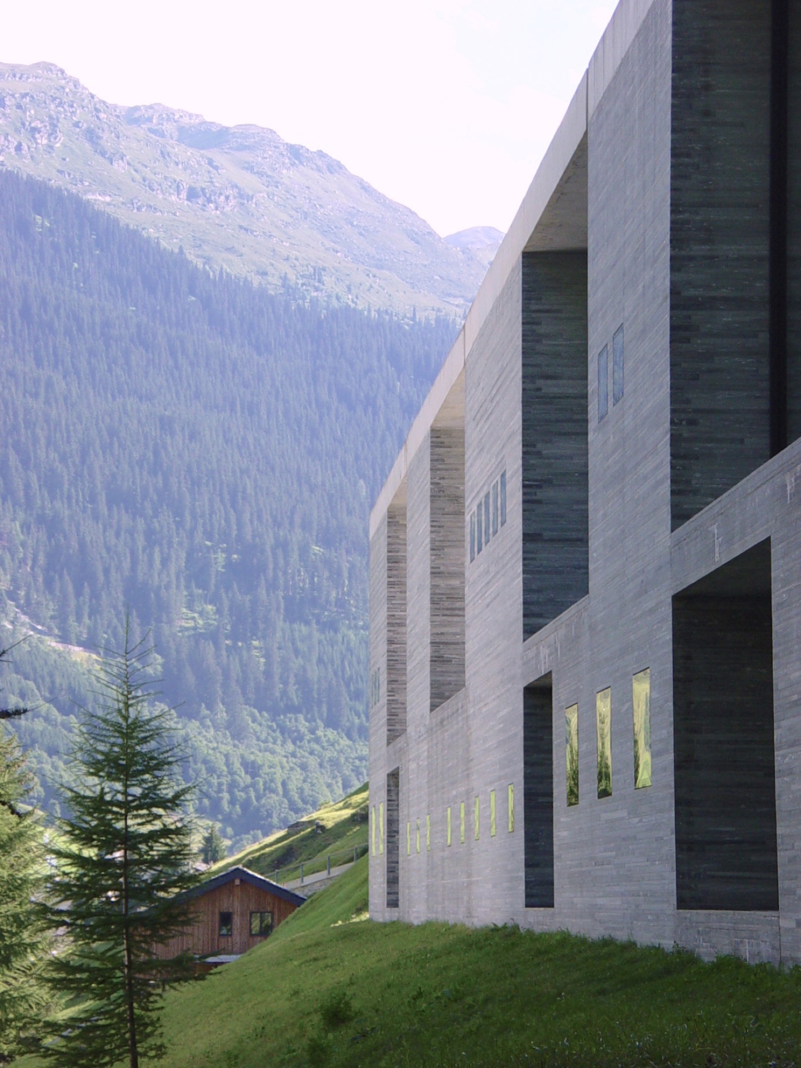 Quarry Bath, a stone bathhouse facade set against a mountain valley